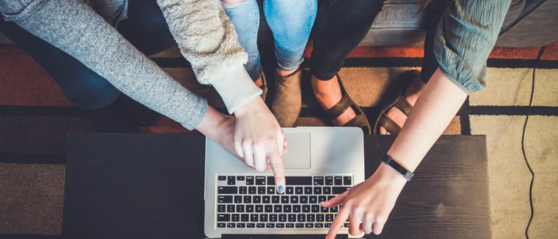 a child and two adults are sitting in front of a laptop, pointing at different parts of the screen